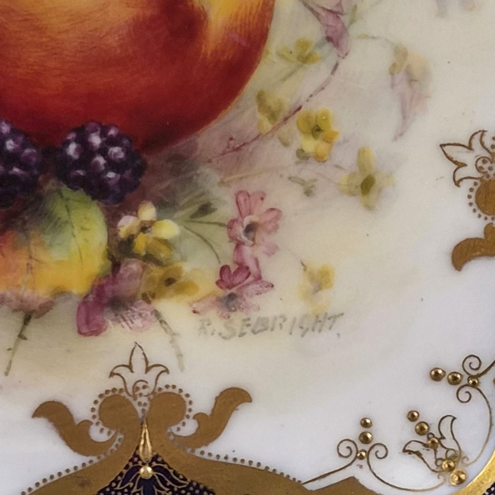 A circular porcelain cabinet plate featuring a central hand-painted fruit study surrounded by an ornate cobalt blue and heavily gilded scalloped rim. View IV