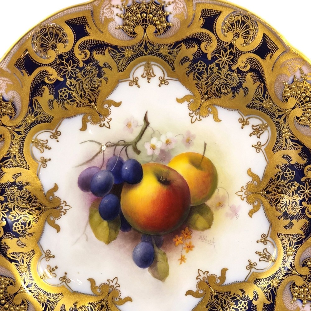 A circular porcelain cabinet plate featuring a central hand-painted motif of apples and grapes surrounded by an ornate cobalt blue and heavily gilded rococo border. View III