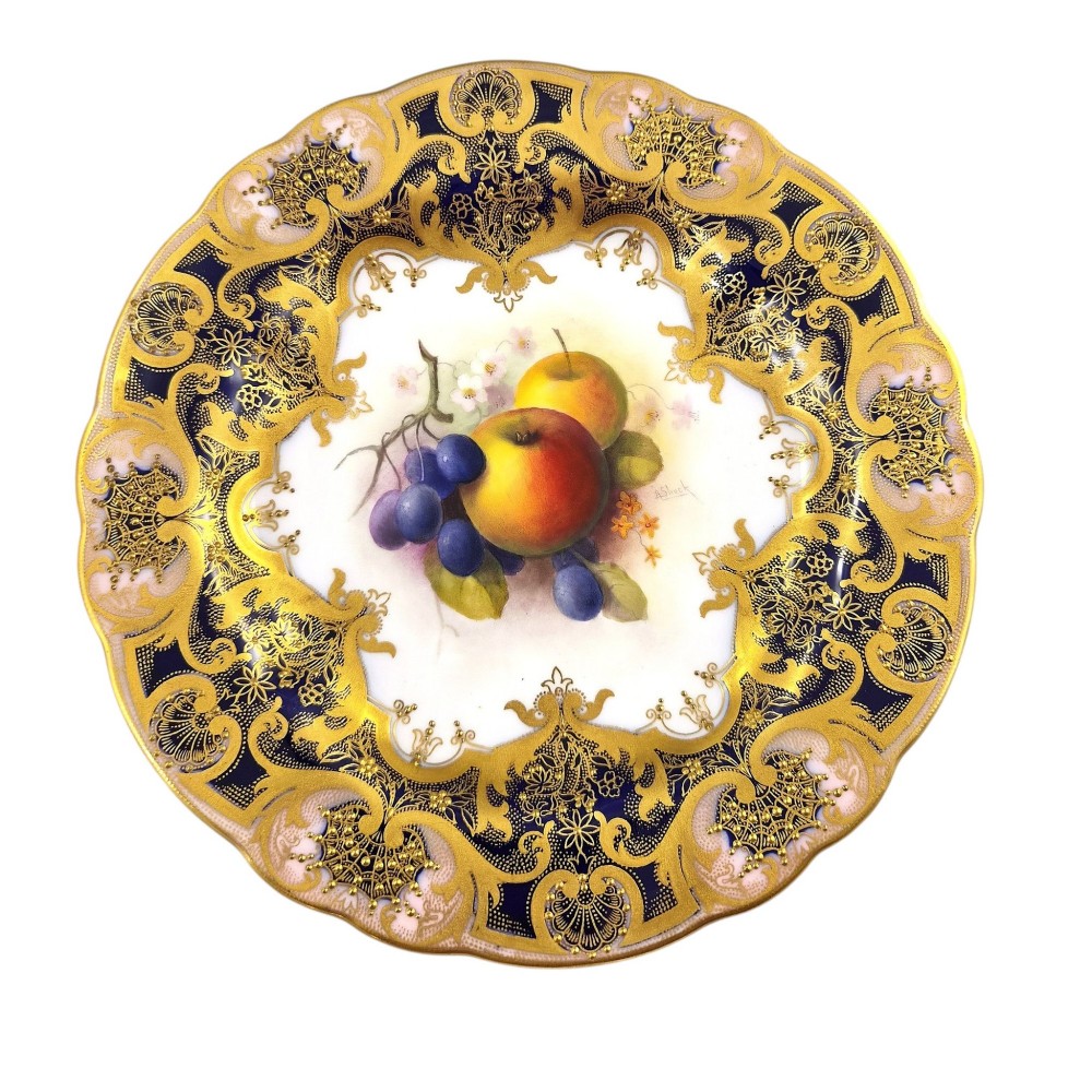 A circular porcelain cabinet plate featuring a central hand-painted motif of apples and grapes surrounded by an ornate cobalt blue and heavily gilded rococo border. View IX