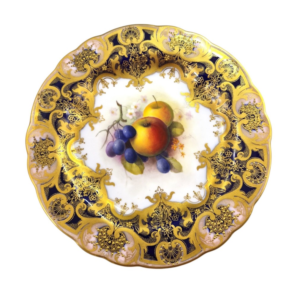 A circular porcelain cabinet plate featuring a central hand-painted motif of apples and grapes surrounded by an ornate cobalt blue and heavily gilded rococo border. View X