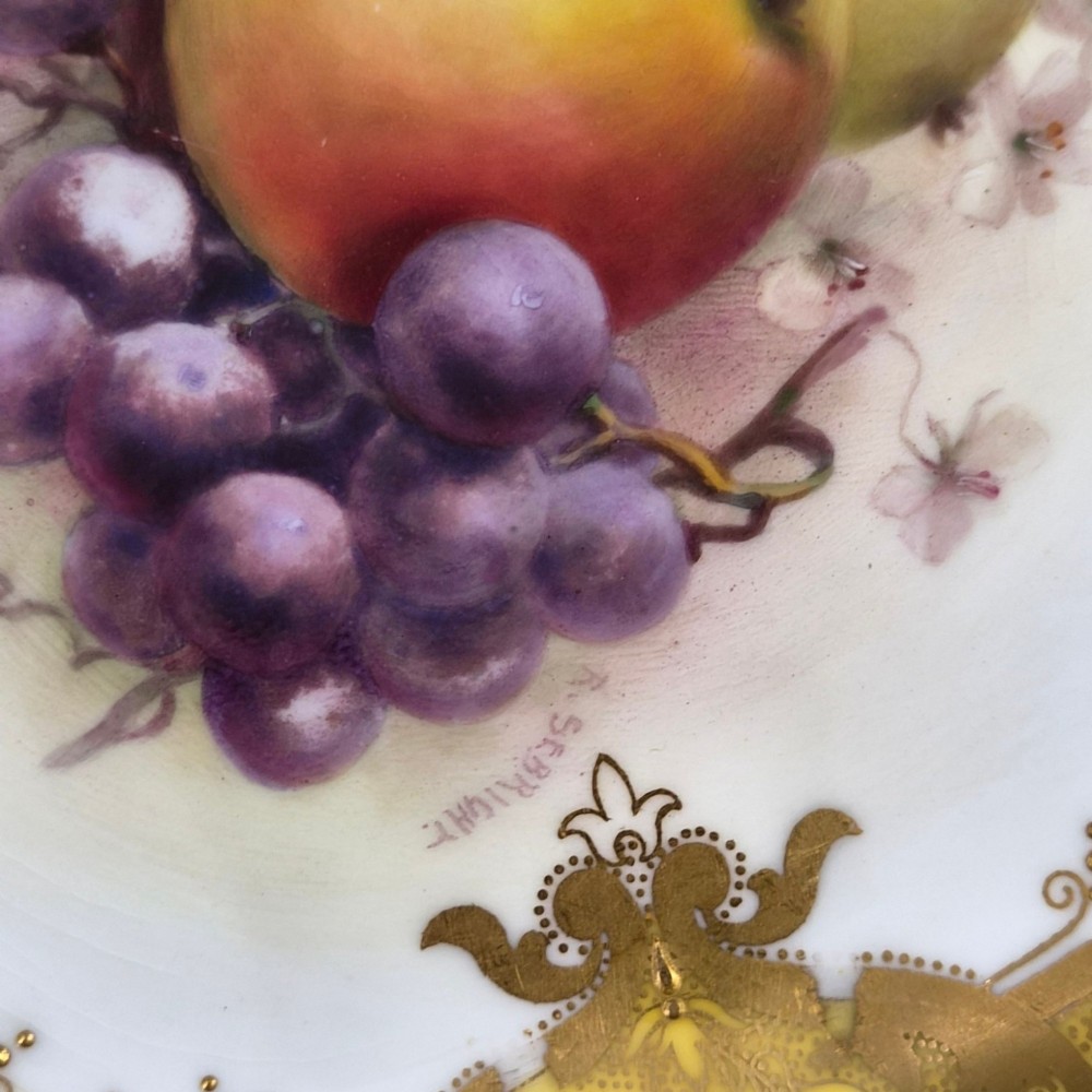 A circular Royal Worcester ceramic cabinet plate featuring a central hand-painted motif of apples and grapes surrounded by a gold gilt and yellow scrollwork border. View IV