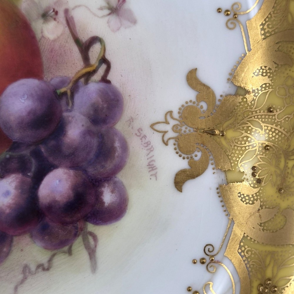 A circular Royal Worcester ceramic cabinet plate featuring a central hand-painted motif of apples and grapes surrounded by a gold gilt and yellow scrollwork border. View V