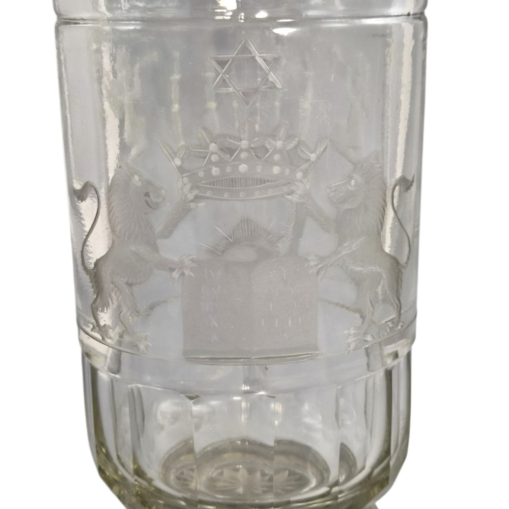A large clear glass beaker featuring detailed wheel-engraved ceremonial iconography, vertical fluted panels near the lower rim, and a faceted base. View II