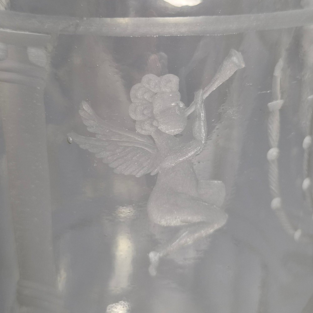 A large clear glass beaker featuring detailed wheel-engraved ceremonial iconography, vertical fluted panels near the lower rim, and a faceted base. View VI