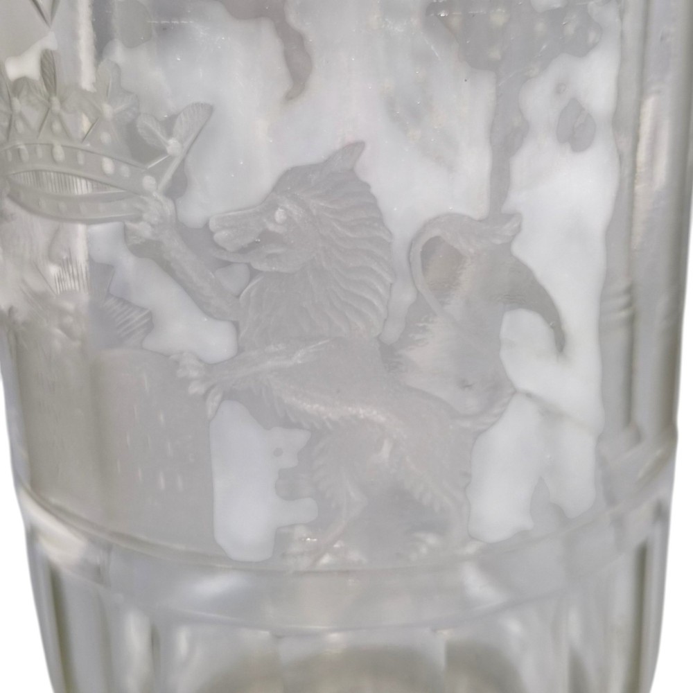 A large clear glass beaker featuring detailed wheel-engraved ceremonial iconography, vertical fluted panels near the lower rim, and a faceted base. View IX