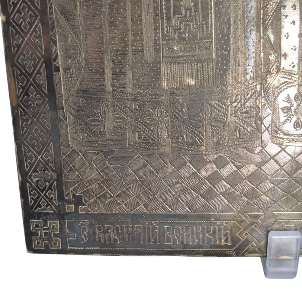 A rectangular antique Orthodox silver icon featuring repousse depictions of the Three Holy Hierarchs with detailed halos and Cyrillic script along the bottom edge. View VI