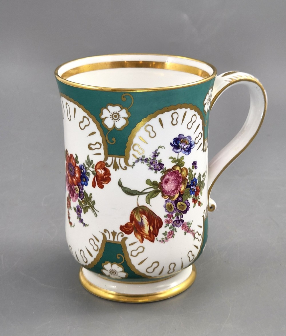 An antique French porcelain cabinet mug featuring a green ground with hand-painted floral bouquets and gilt scroll detailing. View VII