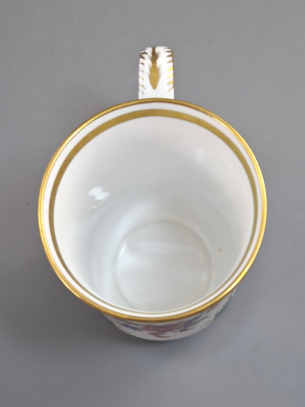 An antique French porcelain cabinet mug featuring a green ground with hand-painted floral bouquets and gilt scroll detailing. View VIII