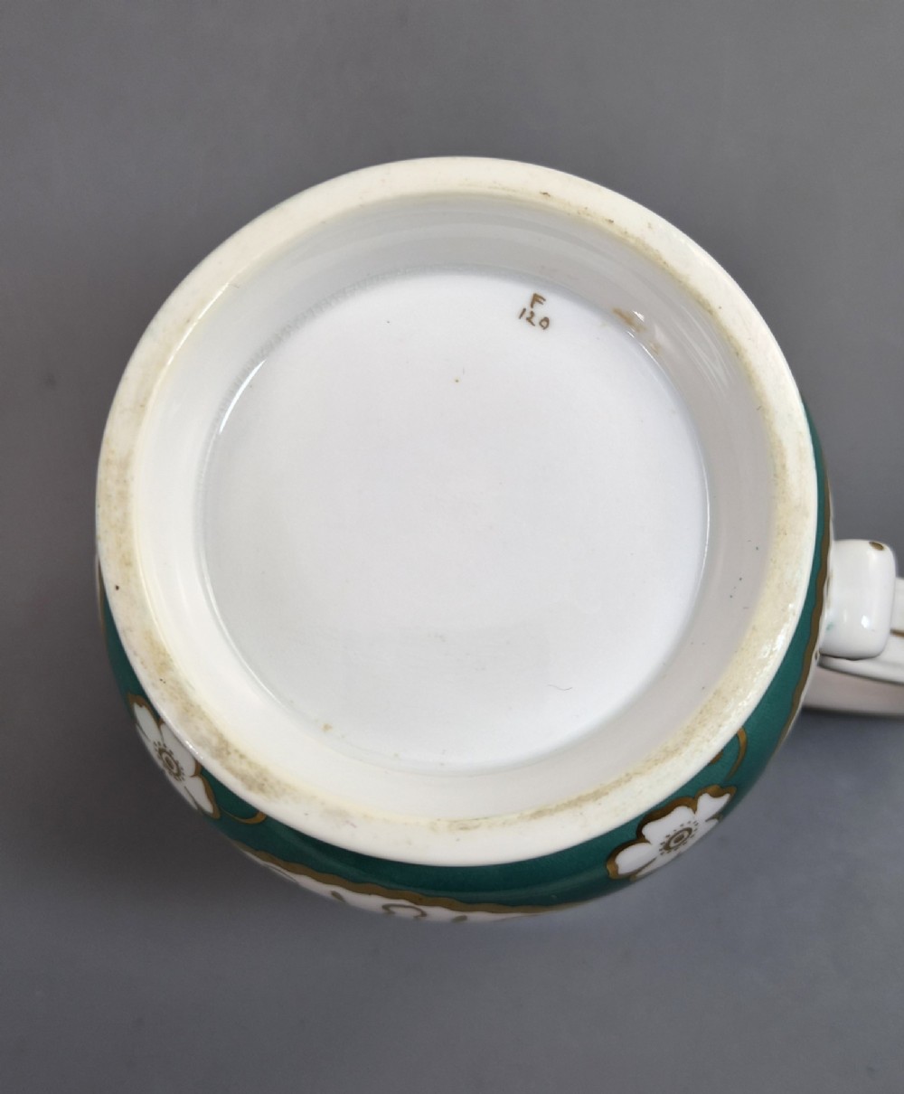 An antique French porcelain cabinet mug featuring a green ground with hand-painted floral bouquets and gilt scroll detailing. View IX