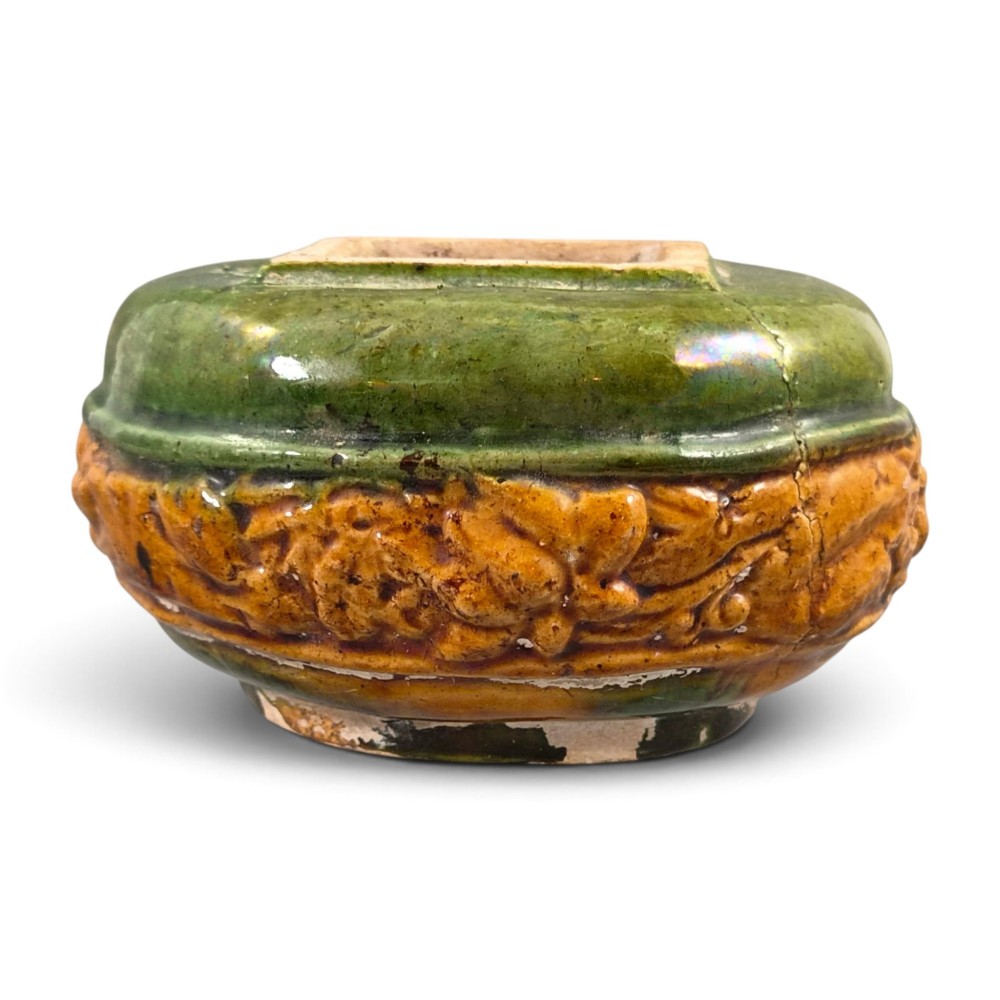 A squat antique Chinese ceramic water vessel featuring a green glazed upper shoulder, a square rim, and an amber-glazed moulded floral band around the middle.