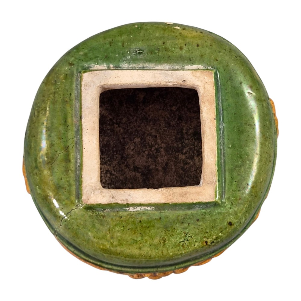 A squat antique Chinese ceramic water vessel featuring a green glazed upper shoulder, a square rim, and an amber-glazed moulded floral band around the middle. View V