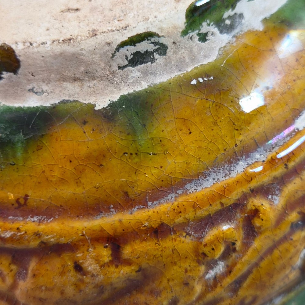 A squat antique Chinese ceramic water vessel featuring a green glazed upper shoulder, a square rim, and an amber-glazed moulded floral band around the middle. View IX