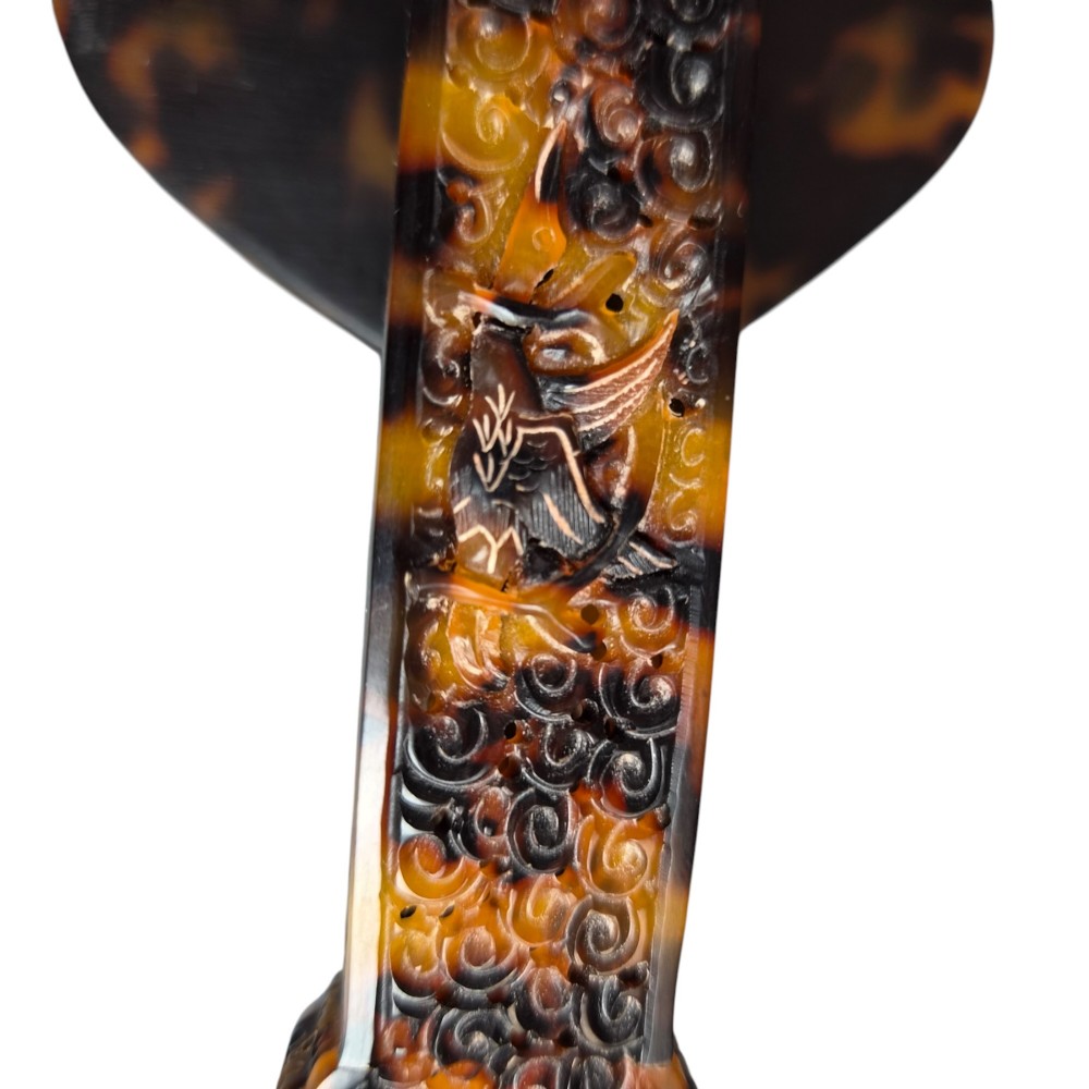A late 19th-century Chinese Qing Dynasty ruyi sceptre carved from translucent mottled amber and dark brown tortoiseshell with intricate relief carving along the handle and head. View XII