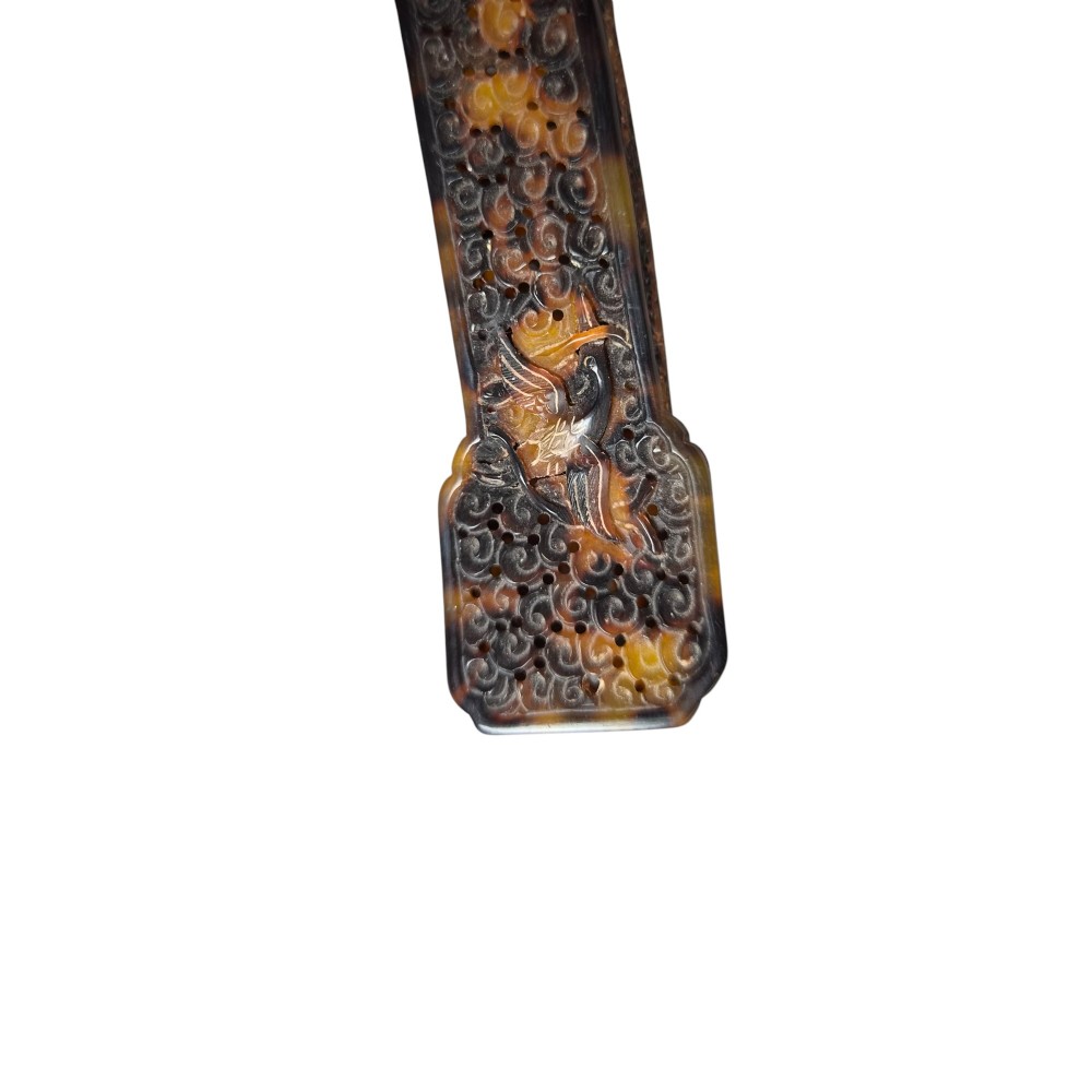 A late 19th-century Chinese Qing Dynasty ruyi sceptre carved from translucent mottled amber and dark brown tortoiseshell with intricate relief carving along the handle and head. View XIV
