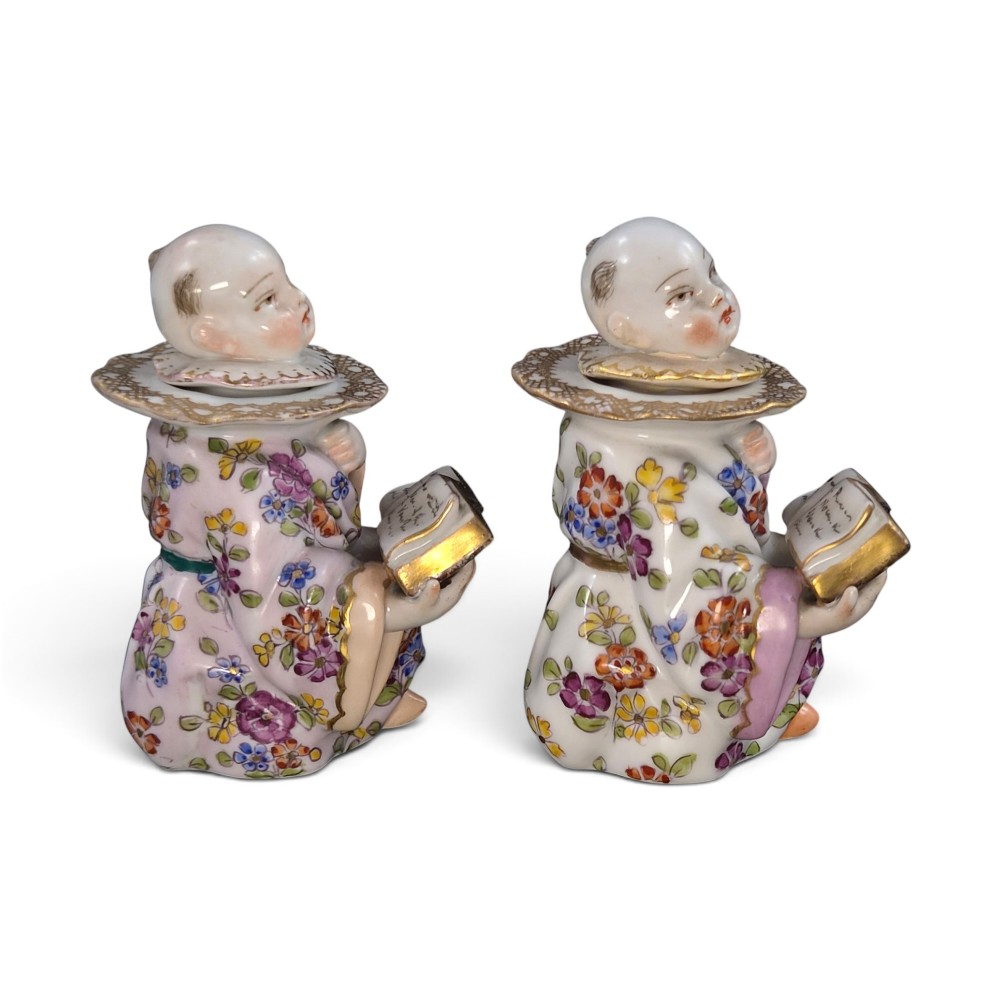 A pair of antique French Samson porcelain figural inkwells depicting singing boys wearing floral robes and gilt-rimmed ruffs while holding open songbooks. View IV