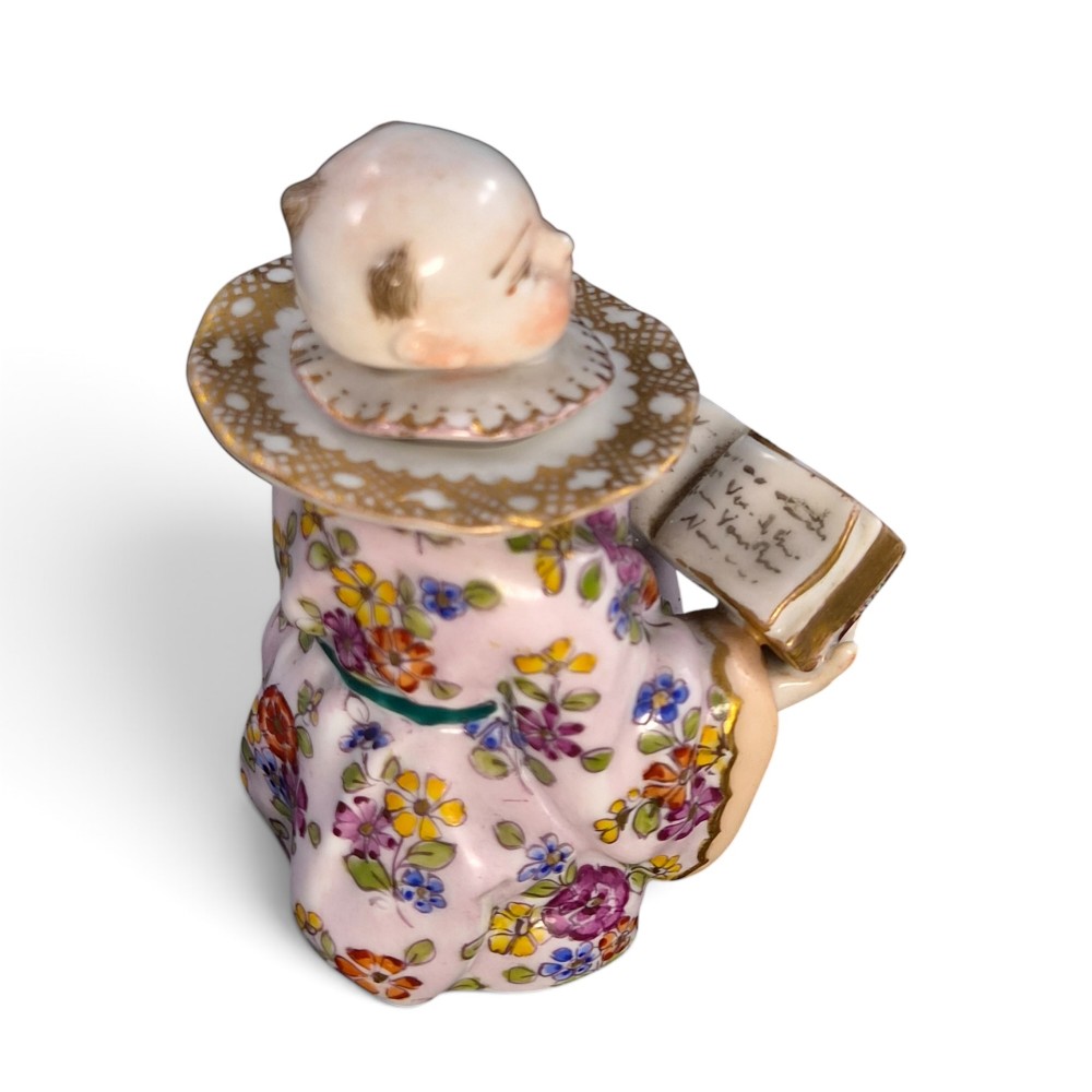 A pair of antique French Samson porcelain figural inkwells depicting singing boys wearing floral robes and gilt-rimmed ruffs while holding open songbooks. View V