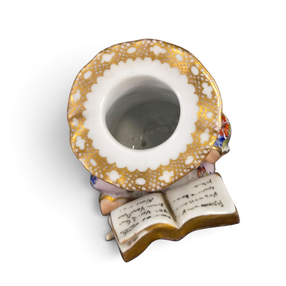 A pair of antique French Samson porcelain figural inkwells depicting singing boys wearing floral robes and gilt-rimmed ruffs while holding open songbooks. View VI