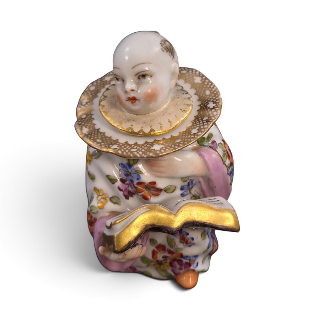 A pair of antique French Samson porcelain figural inkwells depicting singing boys wearing floral robes and gilt-rimmed ruffs while holding open songbooks. View IX