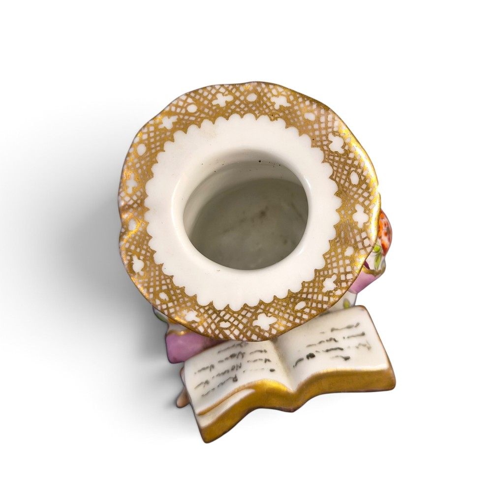 A pair of antique French Samson porcelain figural inkwells depicting singing boys wearing floral robes and gilt-rimmed ruffs while holding open songbooks. View X