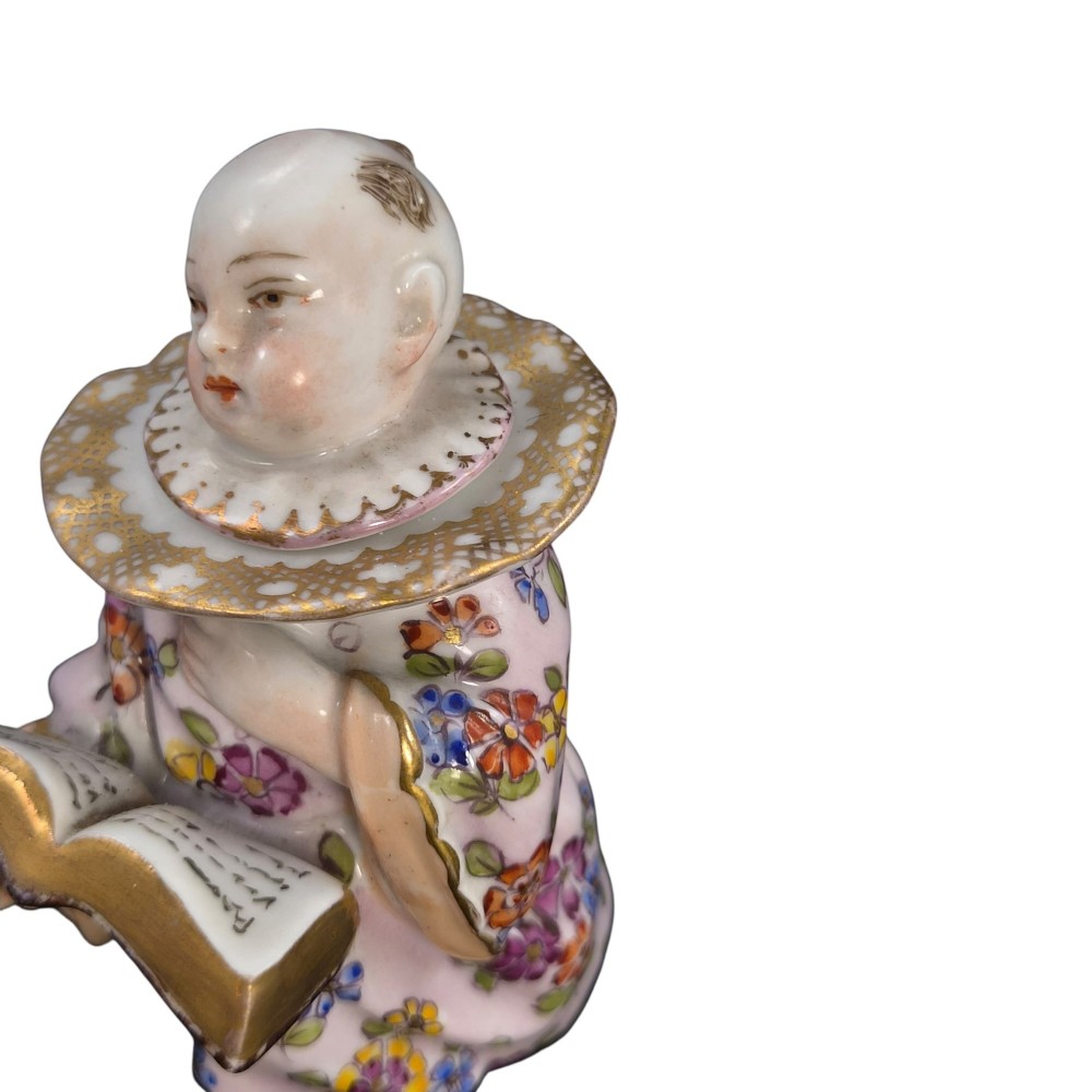 A pair of antique French Samson porcelain figural inkwells depicting singing boys wearing floral robes and gilt-rimmed ruffs while holding open songbooks. View XIV