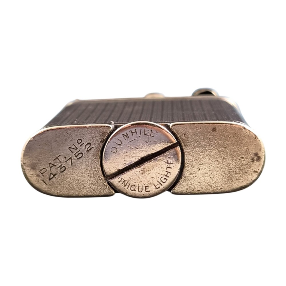 A 1920s Dunhill Unique gold-plated petrol lighter featuring an engine-turned pattern and a straight-arm lift mechanism. View V