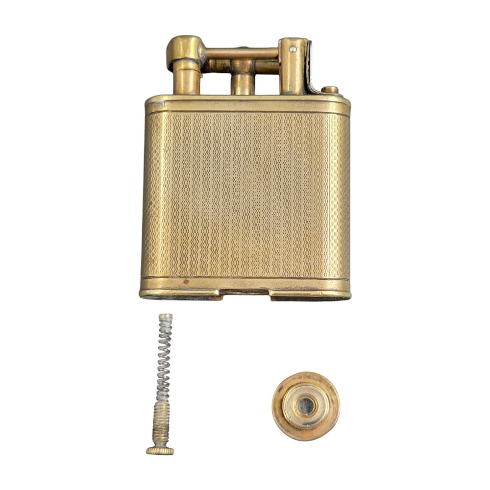 A 1920s Dunhill Unique gold-plated petrol lighter featuring an engine-turned pattern and a straight-arm lift mechanism. View IX