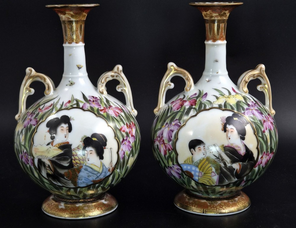 A pair of Japanese Yokohama porcelain vases decorated with hand-painted figures, floral irises, twin gilt handles, and gilded neck details.