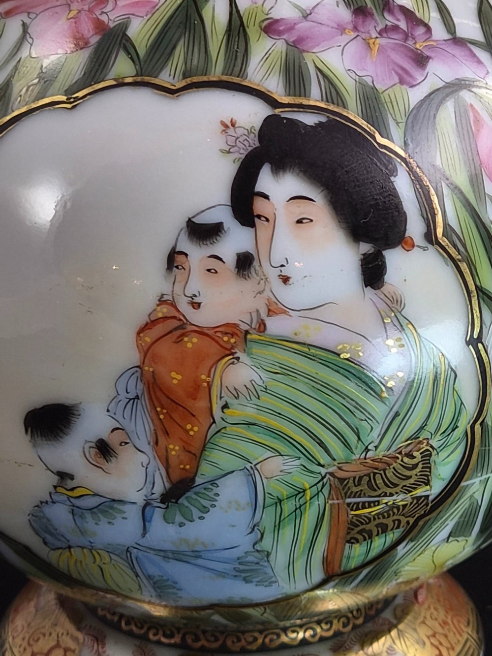 A pair of Japanese Yokohama porcelain vases decorated with hand-painted figures, floral irises, twin gilt handles, and gilded neck details. View VII