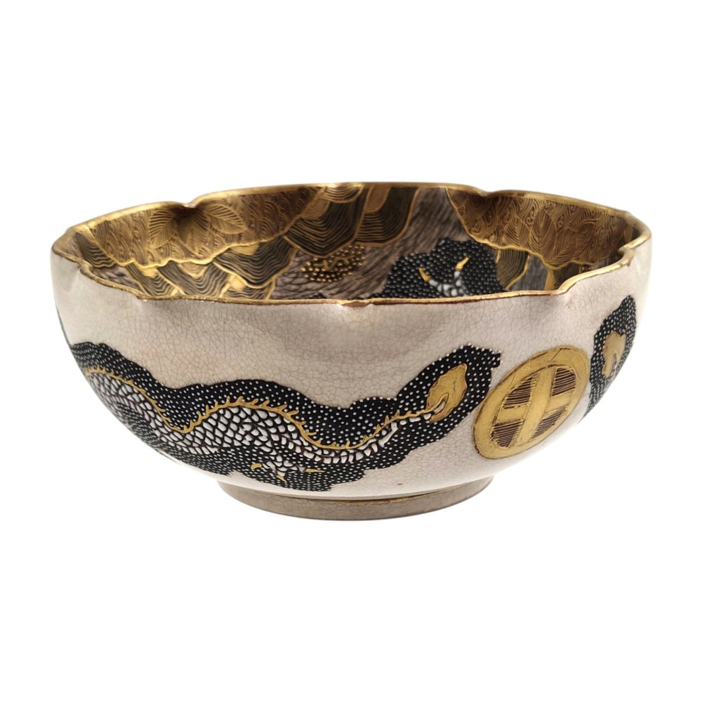 A lobed Japanese Satsuma earthenware bowl featuring detailed hand-painted figures of Rakan and a dragon accented with gold enamelling. View II