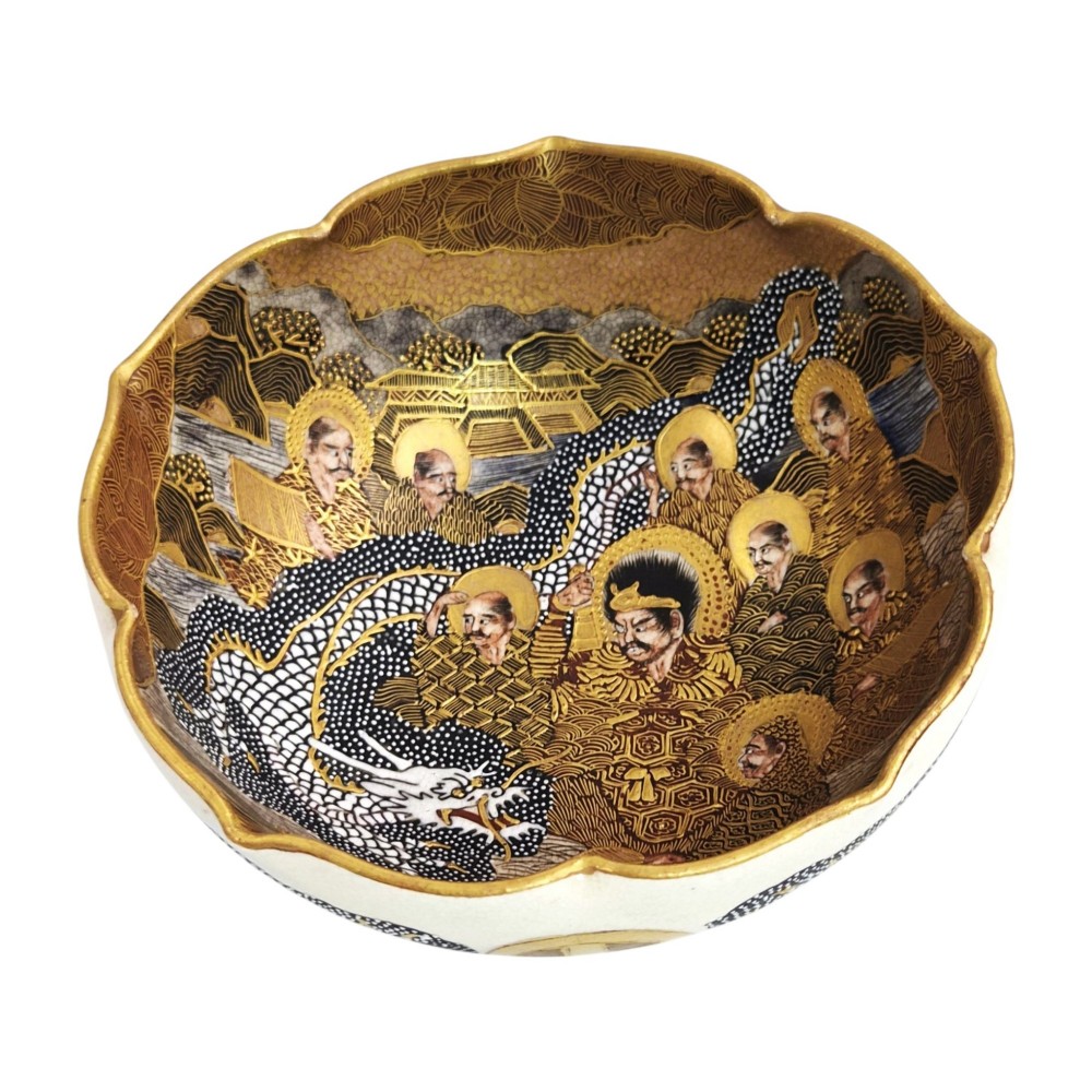 A lobed Japanese Satsuma earthenware bowl featuring detailed hand-painted figures of Rakan and a dragon accented with gold enamelling. View X