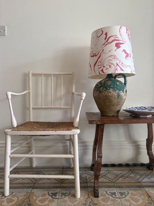 fig 2. A white painted 19th-century turned wood armchair with a spindle back, curved armrests, and a natural woven rush seat.