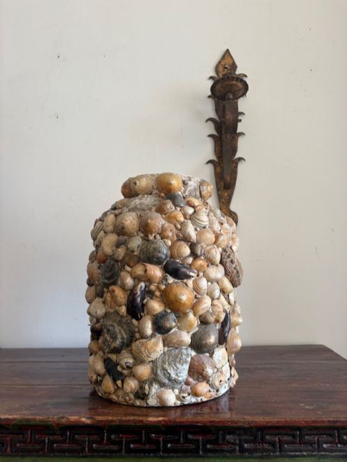 fig 2. A cylindrical antique vase completely encrusted with an assortment of natural sea shells set into a mortar matrix.