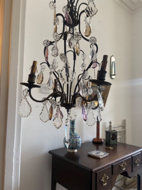 fig 1. A four-branch French Rococo style gilt bronze chandelier decorated with clear, grey, and violet crystal drops.