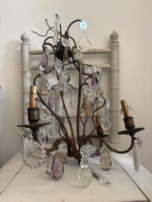 fig 2. A four-branch French Rococo style gilt bronze chandelier decorated with clear, grey, and violet crystal drops.