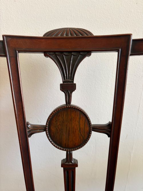 fig 1. A late 18th-century Georgian mahogany open armchair featuring a carved back splat with a central rosewood roundel, swept armrests, and reddish-brown fabric upholstery.
