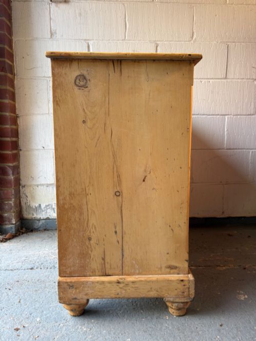 fig 3. A nineteenth-century scrubbed pine chest of drawers with two small drawers above two long drawers featuring dark turned bun handles.