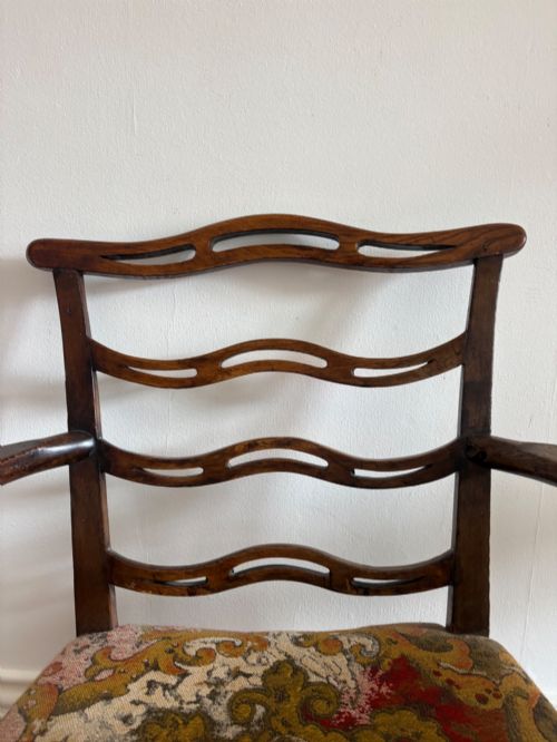 fig 1. A George III elm ladderback open armchair featuring scrolled armrests and a patterned upholstered seat with fringed trim.