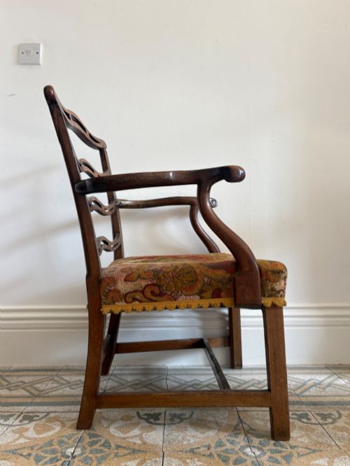 fig 2. A George III elm ladderback open armchair featuring scrolled armrests and a patterned upholstered seat with fringed trim.