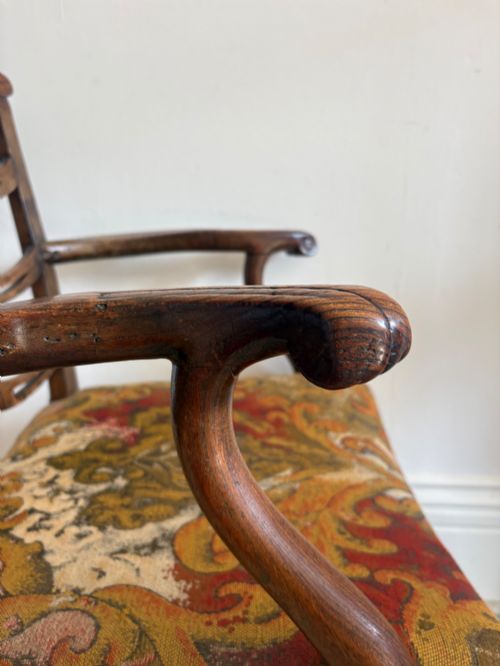 fig 3. A George III elm ladderback open armchair featuring scrolled armrests and a patterned upholstered seat with fringed trim.
