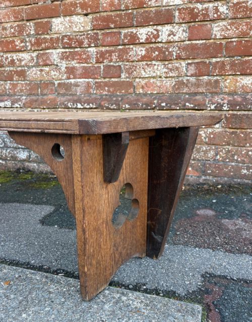 fig 2. A long curved oak bench featuring trefoil carved cut-outs on the end supports.