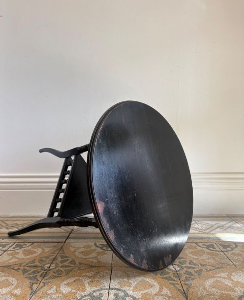 fig 1. A late 19th-century ebonised round side table featuring three turned legs, slender splayed feet, and a lower triangular shelf bounded by a spindled gallery.