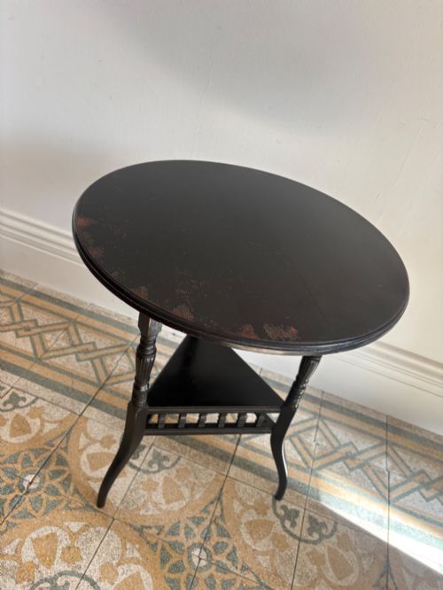 fig 3. A late 19th-century ebonised round side table featuring three turned legs, slender splayed feet, and a lower triangular shelf bounded by a spindled gallery.