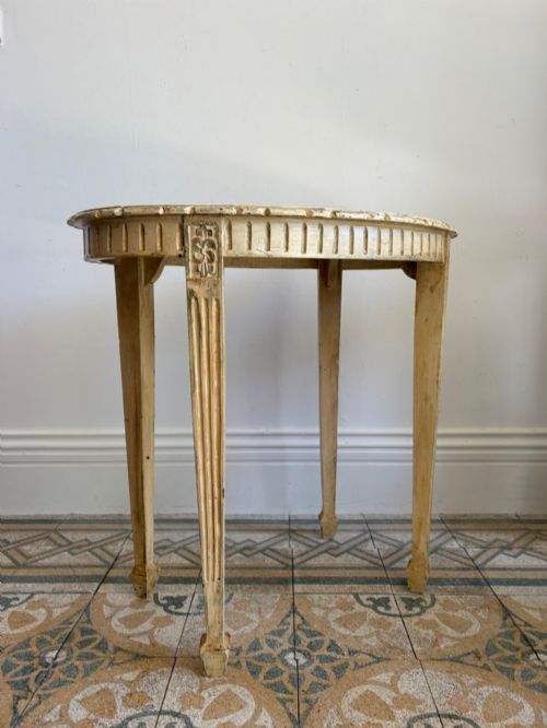 fig 2. An oval cream-painted mahogany occasional table with hand-painted floral garlands, fluted apron, and square tapered fluted legs.