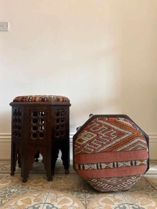 fig 2. A pair of dark wood octagonal stools with turned latticework side panels, arch-cut bases, and geometric woven kilim seat cushions.