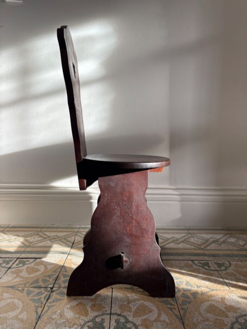 fig 2. An Arts and Crafts dark mahogany hall chair featuring a shaped backrest with a pierced heart cutout and splayed legs.