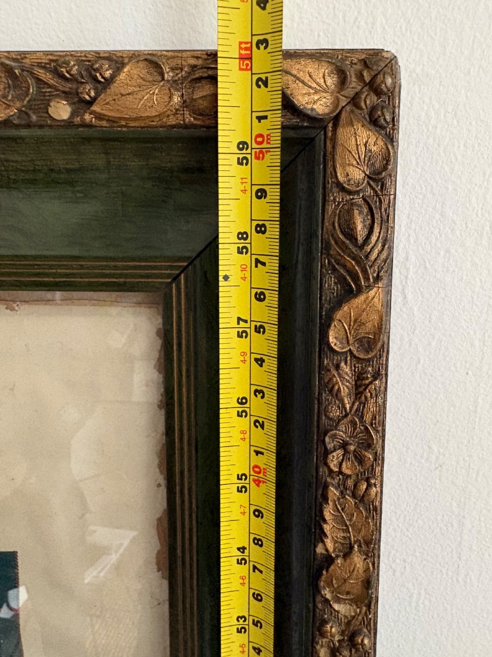 A large, vertically orientated framed paper genealogy chart for Clan Mackinnon featuring two tartan swatches and a central heraldic coat of arms at the top within a dark green and gilt wood frame. View XVI