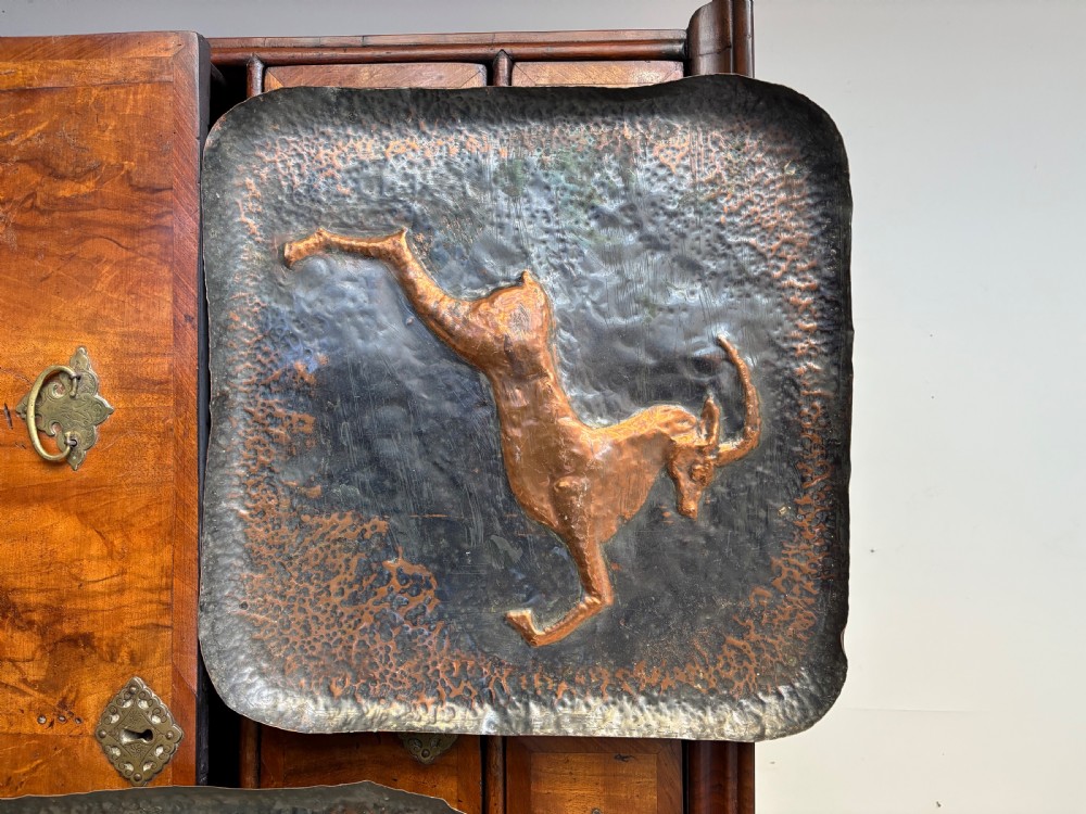 A pair of square late 19th-century hammered metal trays with raised repousse animal figures of an ibex and a feline. View II