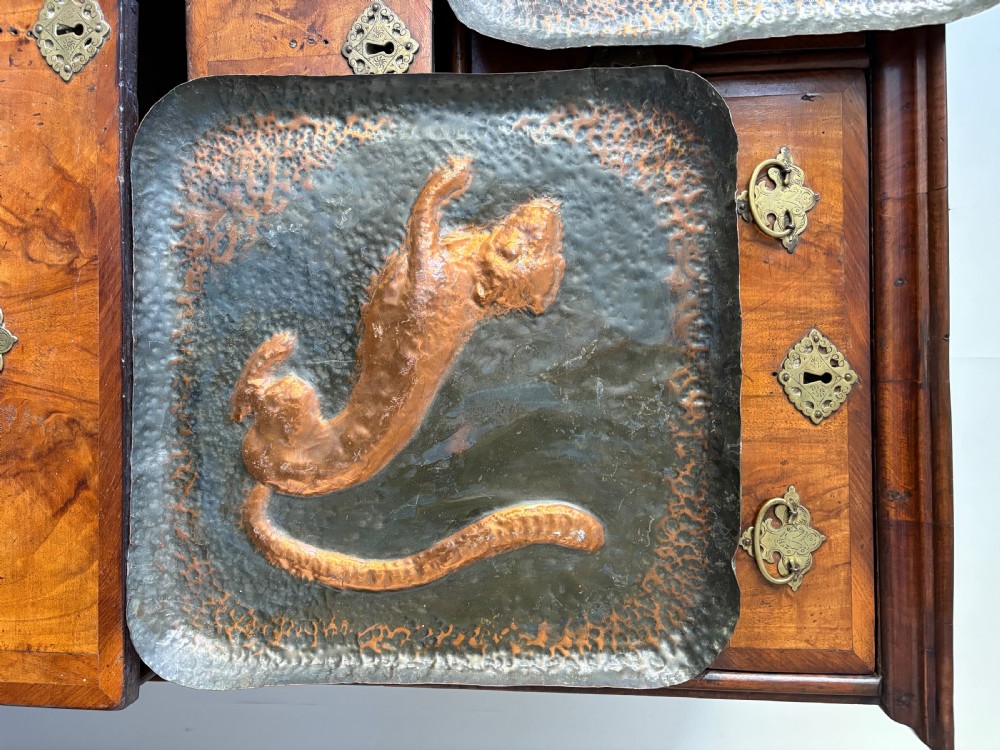 A pair of square late 19th-century hammered metal trays with raised repousse animal figures of an ibex and a feline. View III