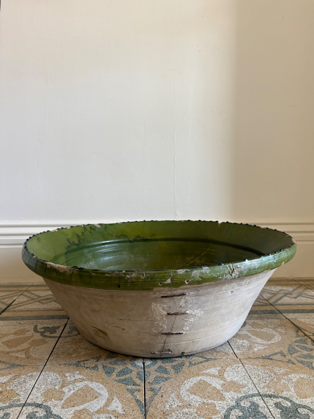 A large 19th-century French earthenware tian bowl featuring an unglazed cream exterior with historical iron staple repairs and a green-glazed interior. View VIII