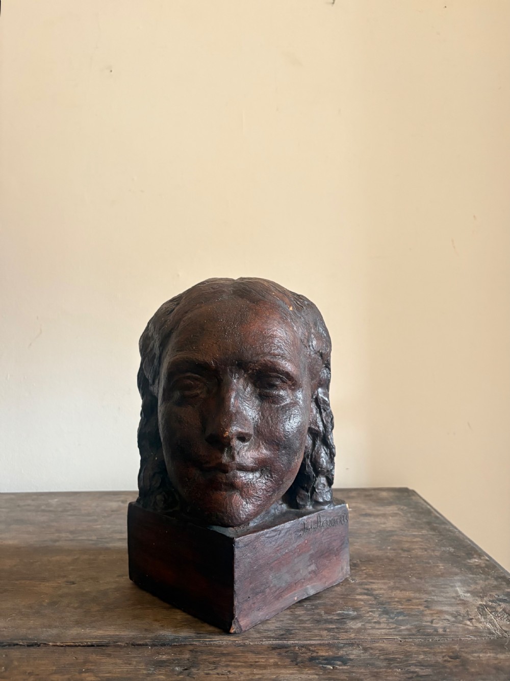 A dark brown 1930s French terracotta bust depicting a female head in profile, resting on an integrated rectangular plinth. View IV